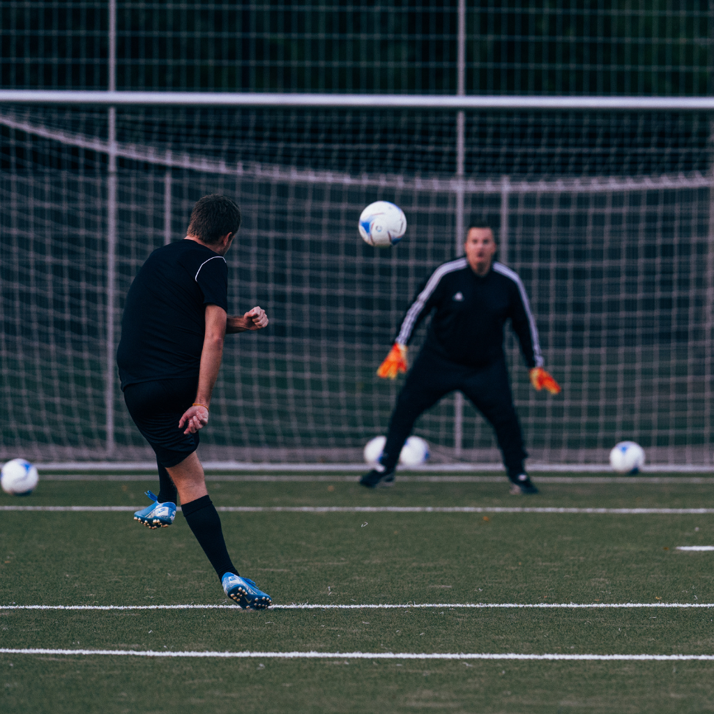 two men playing football in the ground , and there are more balls